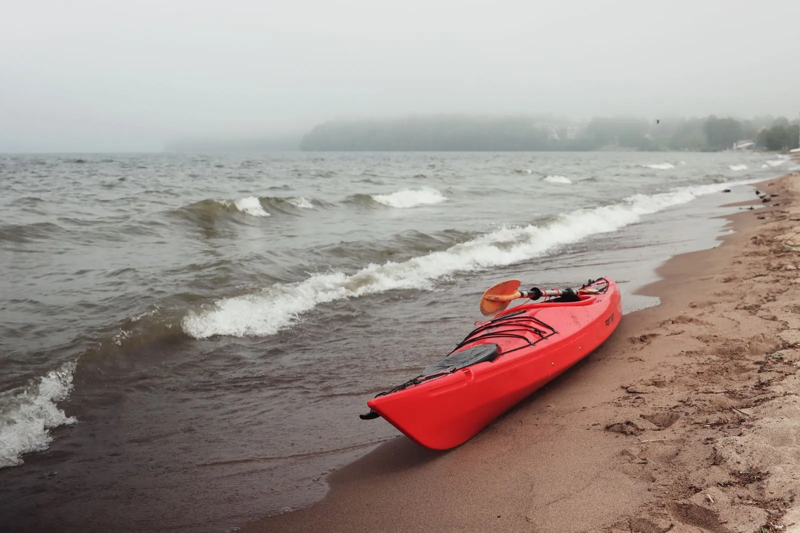 Red kayak on a misty beachside in Jönköping, Sweden. Perfect for outdoor recreation.